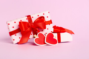 Gift boxes with beautiful bows and hearts on pink background. Valentine's Day celebration