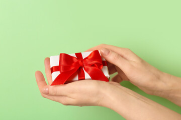 Woman holding gift box with beautiful bow on green background. Valentine's Day celebration