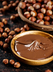 Hazelnut butter and inshell hazelnuts on the table in plates.