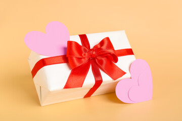 Gift bow with beautiful bow and paper hearts on beige background. Valentine's Day celebration