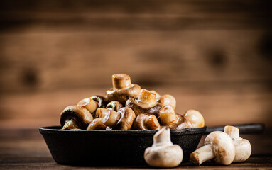 A frying pan with fried mushrooms on the table. 