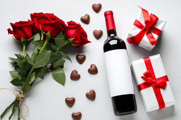Obraz na płótnie Canvas Bottle of wine, chocolate candies, rose flowers and gifts on white background. Valentine's Day celebration