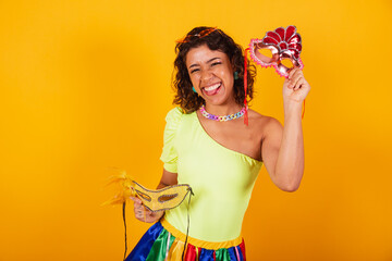 beautiful afro american brazilian woman, in carnival clothes, holding two carnival masks.