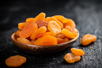 Dried apricots in a wooden plate on the table. 