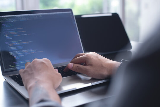Developing programmer, software developer coding computer code on laptop computer. Digital software development. Website and mobile app design and coding technologies.