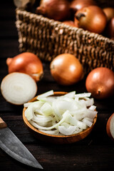 Pieces of onion in a plate and whole onions in a box. 