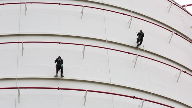 Male two worker down height tank shell plate rope ladder  access safety inspection of thickness storage tank gas propane.