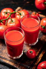 Tomato juice in glasses on a wooden cutting board. 