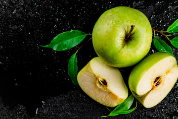 Pieces and a whole apple with leaves on the table. 