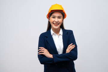 Portrait of Asian female engineer wearing hard hat with her arms crossed isolated on grey background.