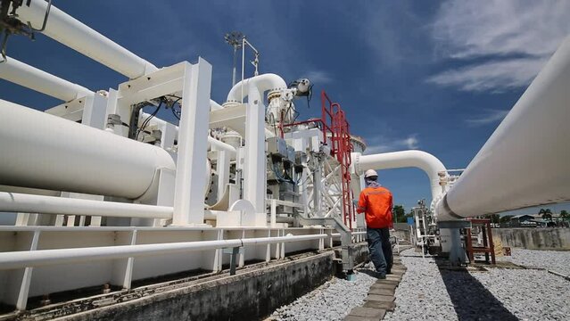 Male worker inspection at steel long pipes and pipe elbow in station oil factory during refinery valve of visual check record pipeline oil and gas industry.