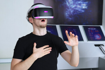 Portrait of happy young handsome man, positive smiling guy using, wearing a modern device virtual reality headset mask or 3D, AR, VR glasses, playing the game. People and technology metaverse concept.