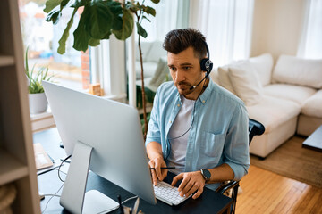 Businessman typing email while using computer and working at home.