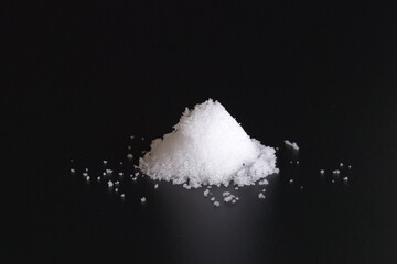 A white powdery mass of salt on a black background.