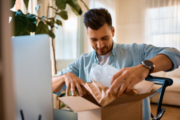 Happy man unboxing home delivered package.