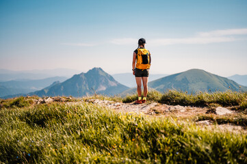 Young traveler hiking girl with backpacks. Hiking in mountains. Sunny landscape. Tourist traveler....