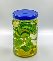 Cucumbers lemons and mint leaves are in a jar with water