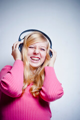 blond teenager girl listening music on earphones and smiling 