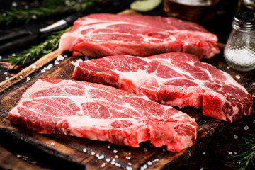 Raw pork steak on a wooden cutting board. 