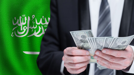 Hands holding dollar money on flag of Saudi Arabia