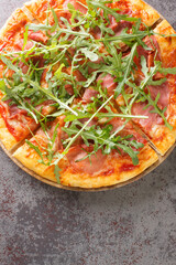 Delicious pizza with prosciutto and arugula closeup Italian snacks. Vertical top view from above