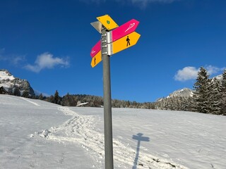 Hiking markings and orientation signs with signposts for navigating in the idyllic winter ambience over the Lake Walen or Lake Walenstadt (Walensee) and in the Swiss Alps, Amden - Switzerland (Schweiz