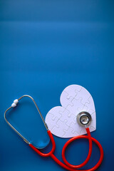 Doctor`s desk in the clinic's office. Stethoscope, puzzle heart, prescriptions on the table.