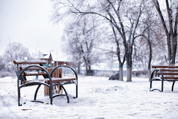 park bench on a winter alley at snowfall. bench with snow after snowstorm or in snow calamity in europe