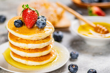 Pancakes with honey and berries on a plate.