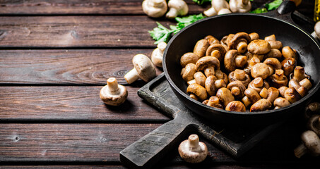 Fragrant homemade fried mushrooms in a frying pan on a cutting board. 