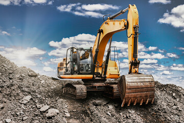 A large yellow excavator moving stone or soil in a quarry. Heavy construction hydraulic equipment. Excavation.