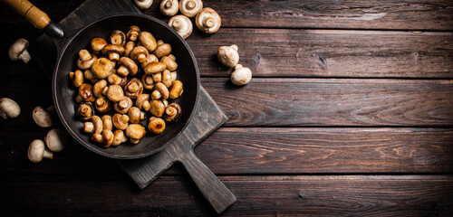 Fragrant homemade fried mushrooms in a frying pan on a cutting board.  - 563534620