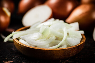 Pieces of onion in a wooden plate on the table.