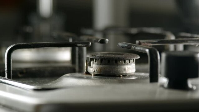 close up view of turning off gas stove, defocused hand turns gas supply valve and stop burner in kitchen in morning. concept of cooking.