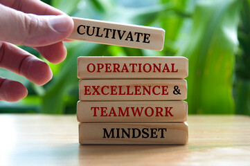 Cultivate operational excellence and teamwork mindset text on wooden blocks with blurred nature background - obrazy, fototapety, plakaty