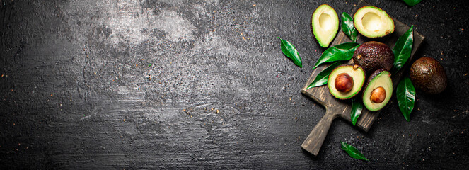 Fototapeta na wymiar Fresh avocado with foliage on a cutting board.
