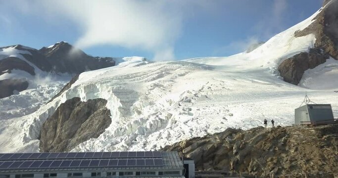 Flying across Gnifetti Refuge near Monte rosa with glaciers ice and snowy mountains in the background during sunset in summer, Alps, Italy