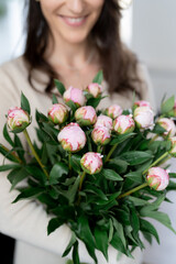 Positive woman holding a huge bouquet of flowers in her office. Birthday present smile.