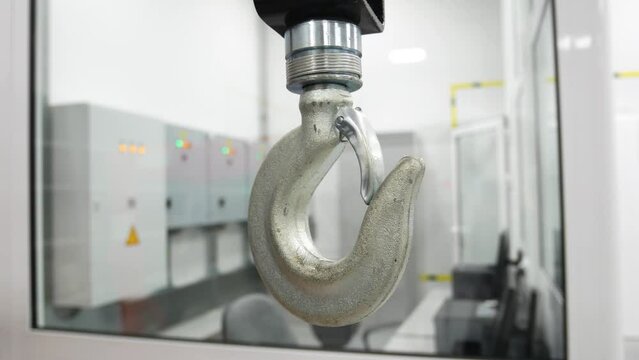A large crane hook in production. White steel hook moves to the side