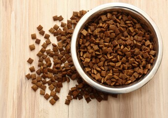 Bowl of pets food i the bowl. Full bowl of cat or dog dried food on wooden table. Flat lay.