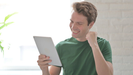 Young Man Cheering Win on Digital Tablet