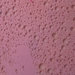 Sparkling pink wine full of small and large bubbles forms an abstract whole on the background of the glass