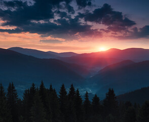 Beautiful landscape in the mountains at sunset. View of colorful sky with clouds and misty hills at distance.