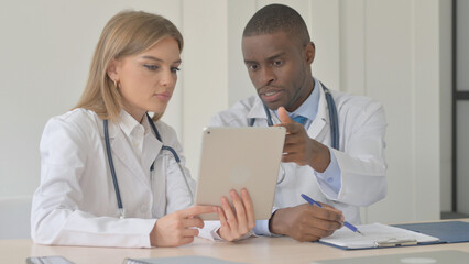 Female Doctor and African Doctor Working in Clinic, Using Tablet