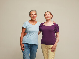 Two pretty old women friends on grey background.