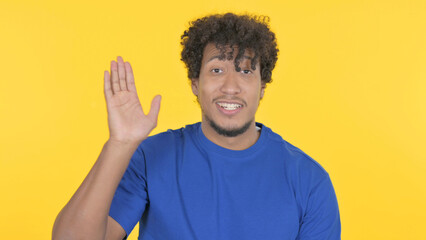 African Man Waving Hand to Say Hello on Yellow Background