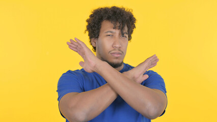African Man Rejecting with Arm Gesture on Yellow Background
