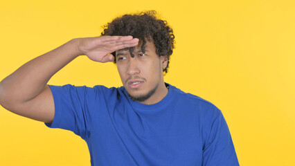 African Man Searching Opportunity on Yellow Background