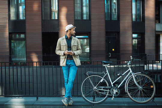 A young man uses a smartphone, social networks, chats with friends. man on the street, standing next to a bicycle.