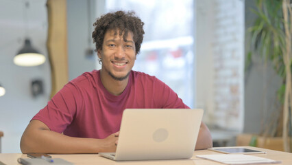 African Man Smiling at Camera while using Laptop